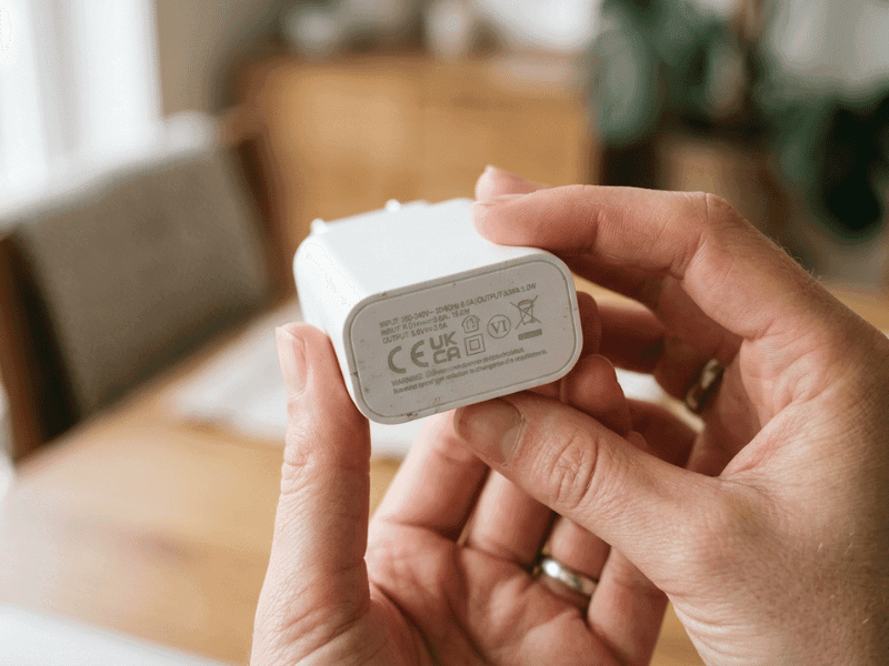 Hand holding a GaN charger showing its specification and safety markings